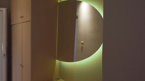 A modern bathroom with a large mirror, built-in cabinets, and a wall-mounted light. - K&C Rooms-Apartments (Markopoulo Mesogaias)