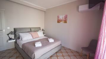 A neatly arranged bedroom with a bed, bedside tables, a chair, and a wall-mounted air conditioner.