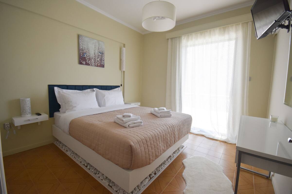 A neatly arranged bedroom with a bed, bedside table, and a TV mounted on the wall.