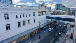 A multi-story building with a classic facade, a car park, and a modern building in the background. - Central Collins Residence at Inner City (Hobart)