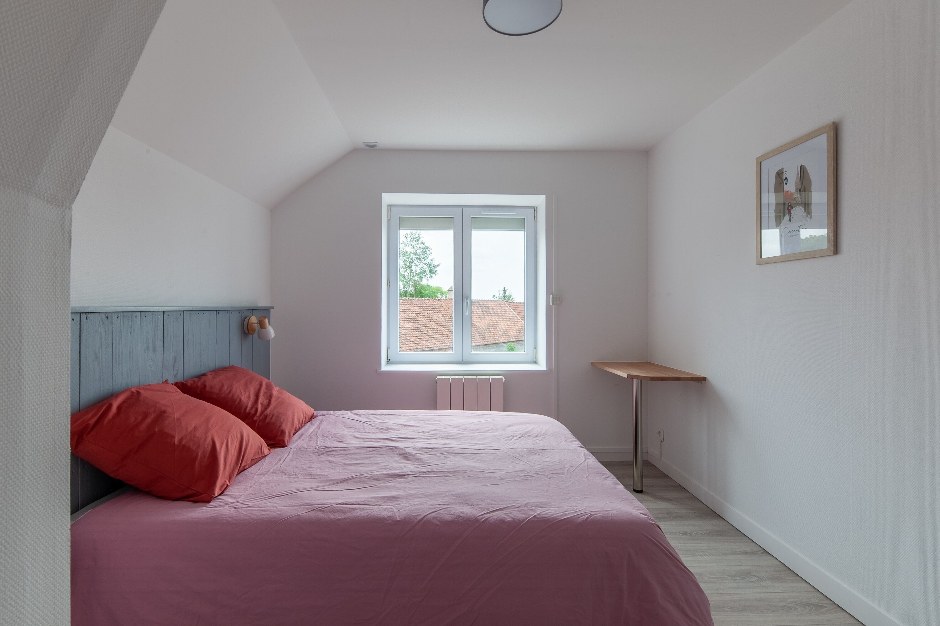 A bedroom with a bed, a window, and a radiator.