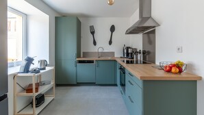 Een moderne keuken met smaragdgroene kastjes, een houten aanrecht en een schaal met fruit.