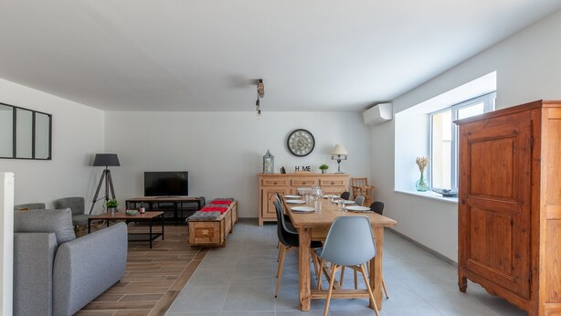 Een moderne woonkamer met een bank, televisie, eettafel en stoelen.