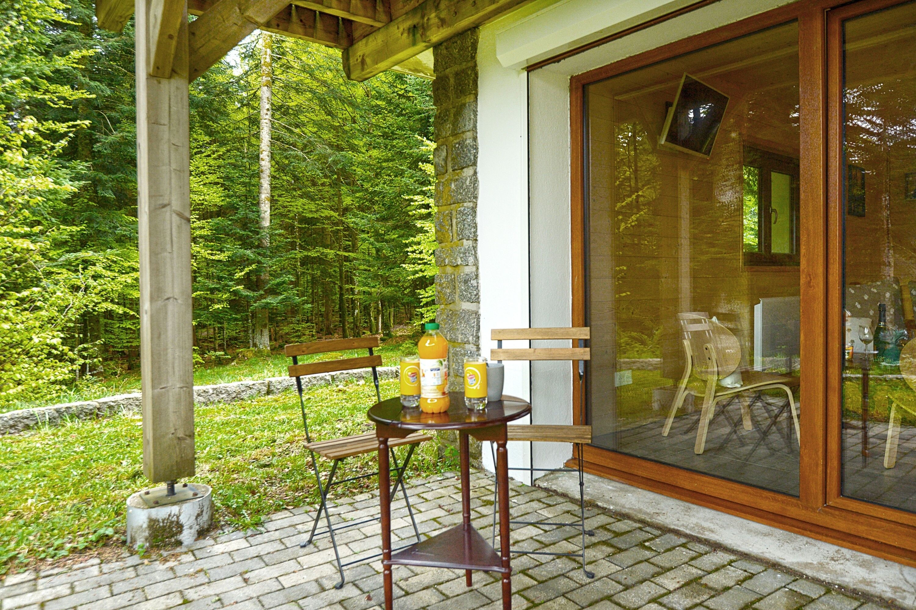 A patio with a table and chairs, a bottle of orange juice, and a glass of water.