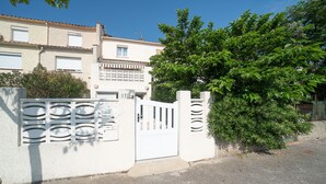 A gated residential area with a white gate, a white wall, and a tree. - Une Maison à la Mer - Proche de la marina (Saint-Cyprien)