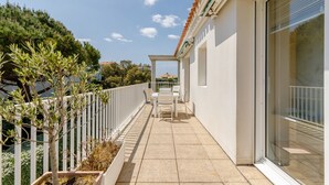 A balcony with a white railing, a table and chairs, and a view of the surrounding greenery and buildings. - L'Hollywood Zen - One Bedroom Apartment, Sleeps 4 (Saint-Jean-de-Monts)