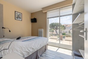 Un dormitorio con una cama grande, un televisor montado en la pared y vistas al balcón.