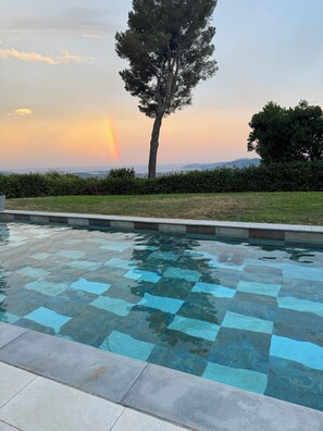 A swimming pool with a checkered pattern, surrounded by a hedge and a tree. - La Roche D'or - Magnifique Villa Avec Piscine et vue mer (Grasse)