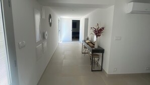 Un hall d’entrée spacieux comprenant un coin repas avec une table et des chaises, un vase rempli de fleurs et une porte donnant sur une autre pièce.