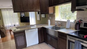 A modern kitchen with dark wooden cabinets, a built-in dishwasher, a stainless steel oven, and a window providing natural light.