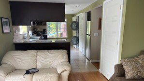 A living room with a beige leather sofa, a brown sofa, a wooden coffee table with a vase of flowers, and two remote controls.