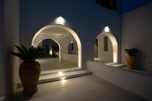 Stroll through a serene outdoor corridor with arched doorways and lush greenery.