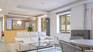 Una sala moderna con una mesa de centro de vidrio, sofá blanco, sillas de mimbre y una mesa de comedor.