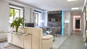 Una sala de estar moderna con una mesa de centro de vidrio, un sofá color beige y un comedor con una mesa y sillas.