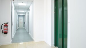 Un pasillo largo y estrecho con paredes blancas y una puerta verde al final.