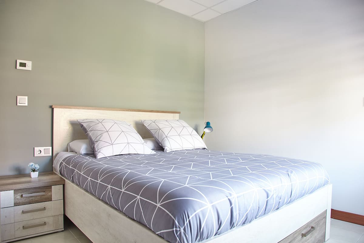 Un dormitorio con cama, mesitas de noche y un velador.