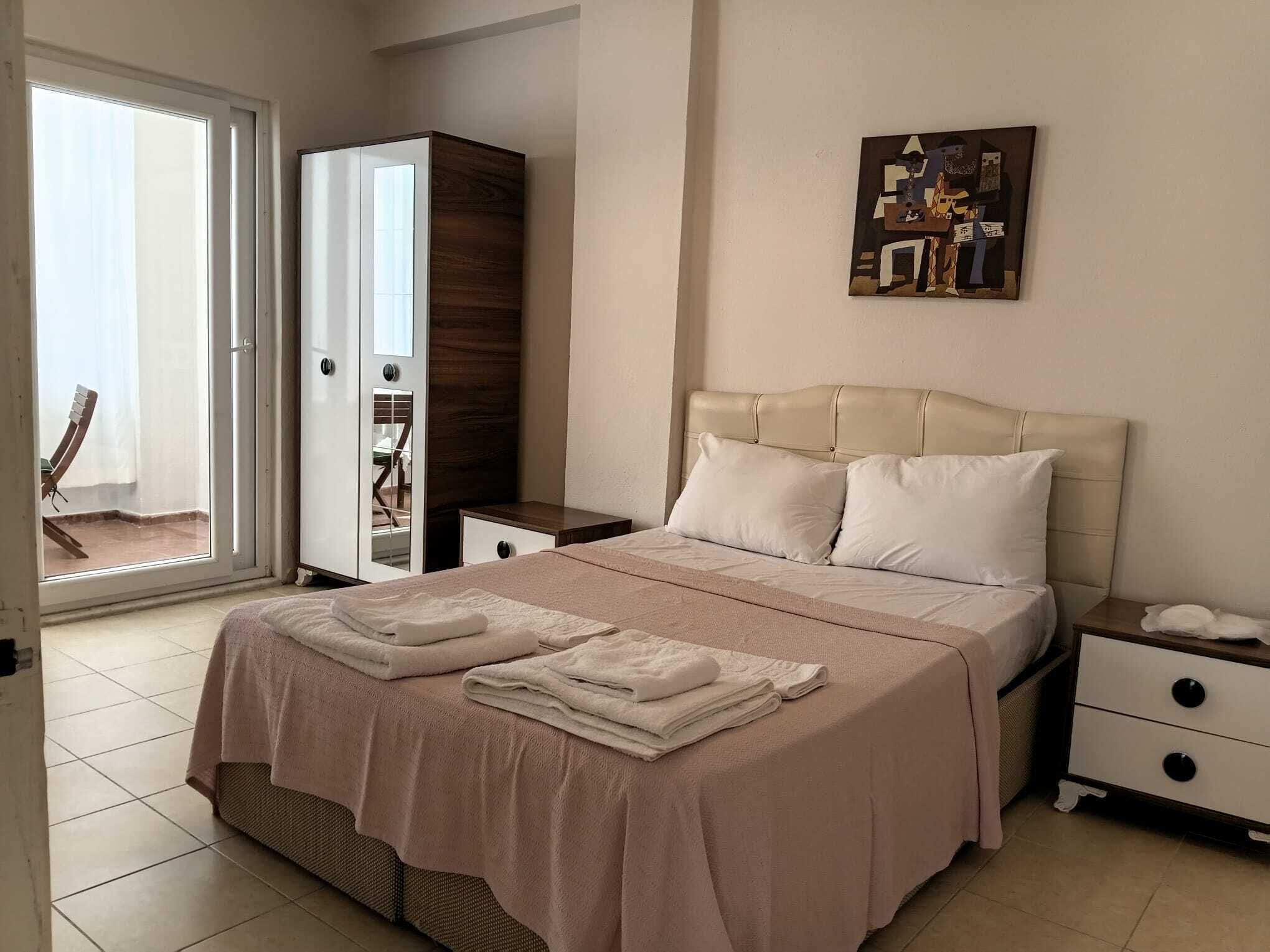 A bedroom with a bed, a nightstand, a wardrobe, and a painting on the wall.