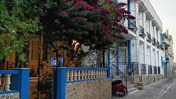 Un hotel con fachada azul y blanca, un muro de piedra y un letrero.