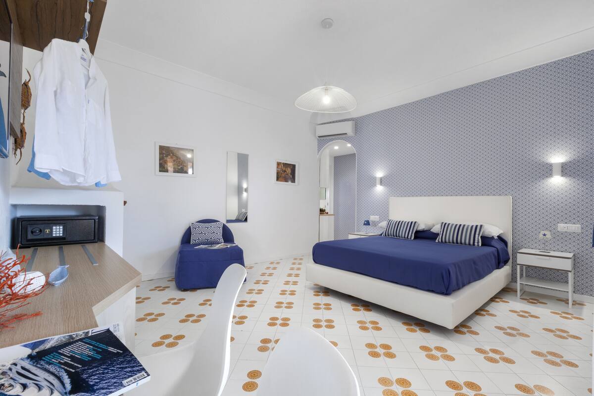 A modern hotel room with a bed, a desk, a chair, and a small table.