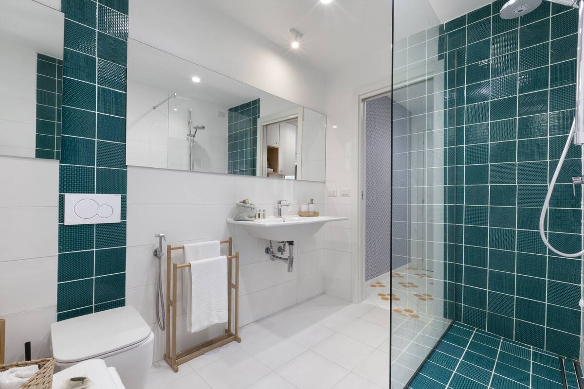A modern bathroom with a shower, sink, and toilet.