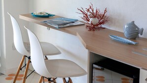 Een moderne eetruimte met een houten tafel, witte stoelen en een decoratieve rode plant.