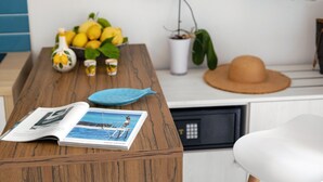Een houten tafel met een tijdschrift, een blauw bord, een fles en een bloempot.
