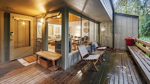 A wooden deck with outdoor seating, a dining area, and a view of the interior.