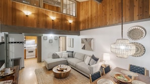 A spacious living area with a large sectional sofa, a dining table with chairs, and a ceiling fan.
