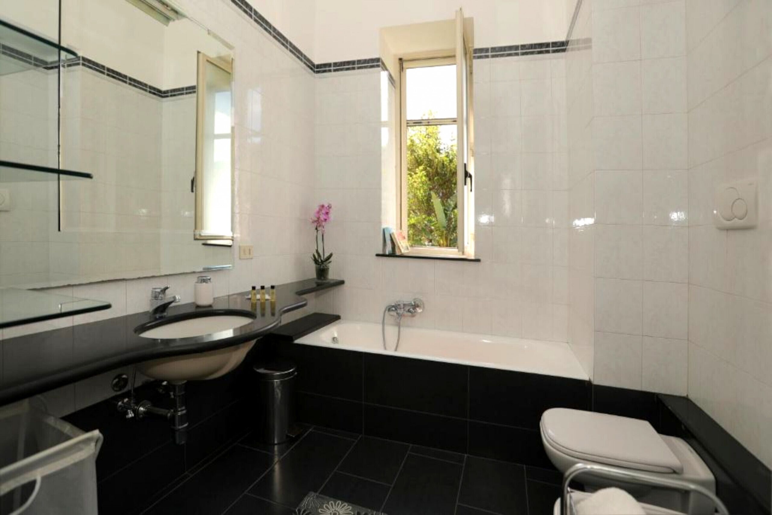 A modern bathroom with a sink, mirror, and bathtub.