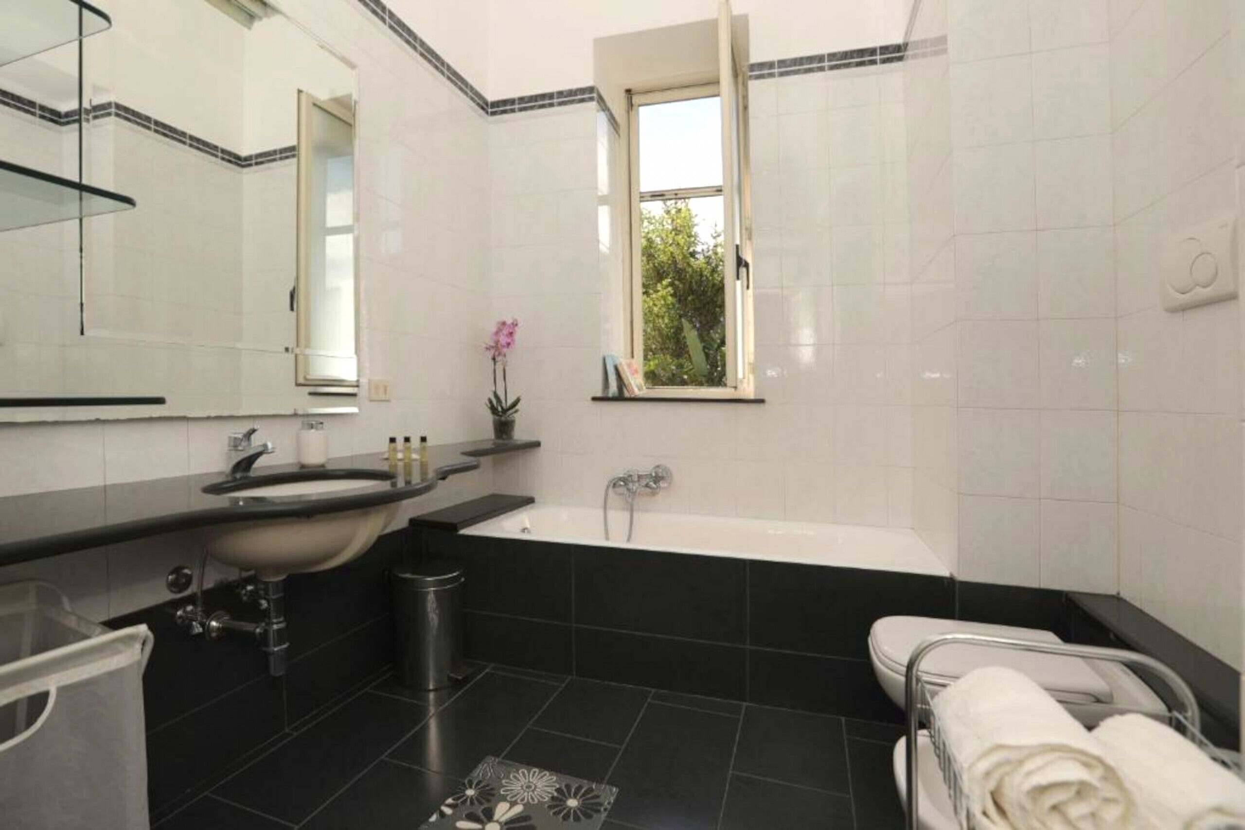Un baño moderno con lavamanos, espejo, bañera y ventana.