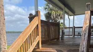 A wooden staircase leading to a covered deck with a view of the water. - St. Johns River Retreat - CSC Unit 1 (Crescent City)