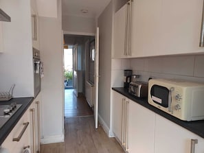 Compact kitchen with modern design, featuring light cabinetry and a dark countertop, microwave, and toaster oven.