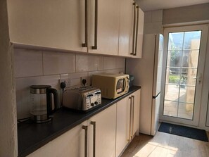 Kitchen features light-colored cabinets, stainless steel appliances, and a microwave, with a glass door leading to an outdoor area.