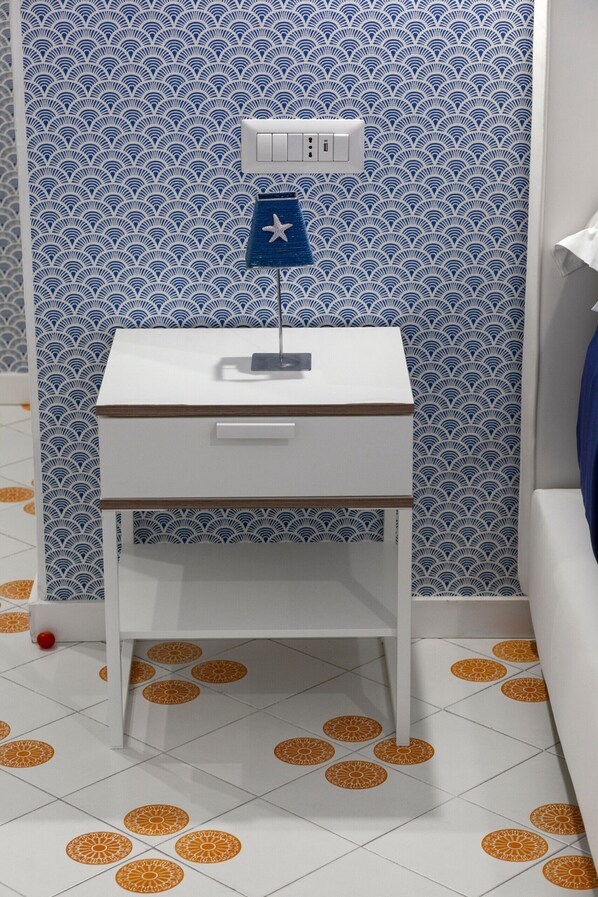 A small white desk with a blue flag ornament and a white switchboard.