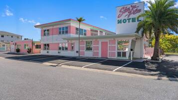 Un motel à la façade rose et blanche, avec une grande enseigne indiquant « Star’s Place Motel », et un parking situé devant.