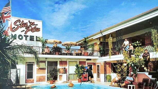 Un motel doté d’une piscine, d’un espace extérieur aménagé et d’un balcon avec des parasols.