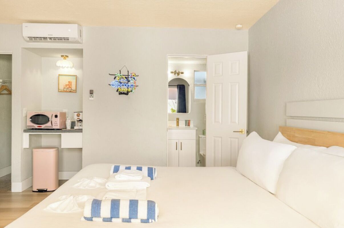 A bedroom with a bed, bedside tables, a microwave, and a small cabinet.