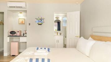 A bedroom with a bed, bedside tables, a microwave, and a small cabinet.