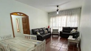 Ein Wohnzimmer mit Esstisch, zwei Sofas, Deckenventilator und einem fenster mit Vorhängen.