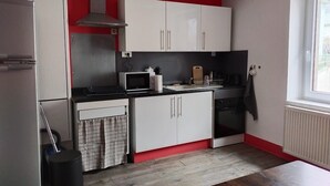A compact kitchen with white cabinets, a microwave, a stove, and a sink.