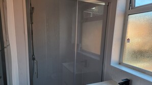 A bathroom with a glass shower enclosure, a white sink, and a window above the sink. - Inviting 3-bed House in Newcastle Upon Tyne (Newcastle-upon-Tyne)