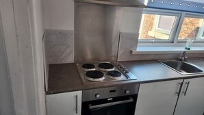 A kitchen with a stainless steel range hood, a gas stove with four burners, a built-in oven, and a window above the sink. - Inviting 3-bed House in Newcastle Upon Tyne (Newcastle-upon-Tyne)