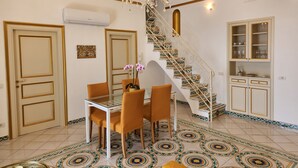 A dining area with a glass table, orange chairs, a chandelier, and a patterned floor.
