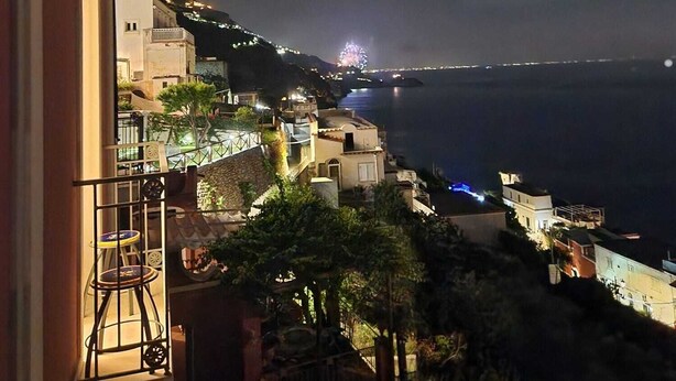 A coastal town at night with buildings illuminated along the hillside.