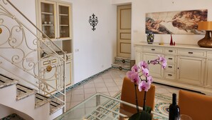 A staircase with ornate metal railings, a glass table with a vase of flowers, and a painting on the wall.