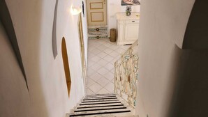 A staircase with a marble floor leading to a room with a white door and a painting on the wall.