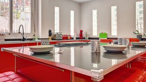 Eine moderne Küche mit einer zentralen Kochinsel, roten Sitzgelegenheiten und großen Fenstern.
