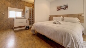 Ein Schlafzimmer mit einem großen Bett, einem Holz-Kopfende, einem Nachttisch und einem an der Wand befestigten Spiegel.