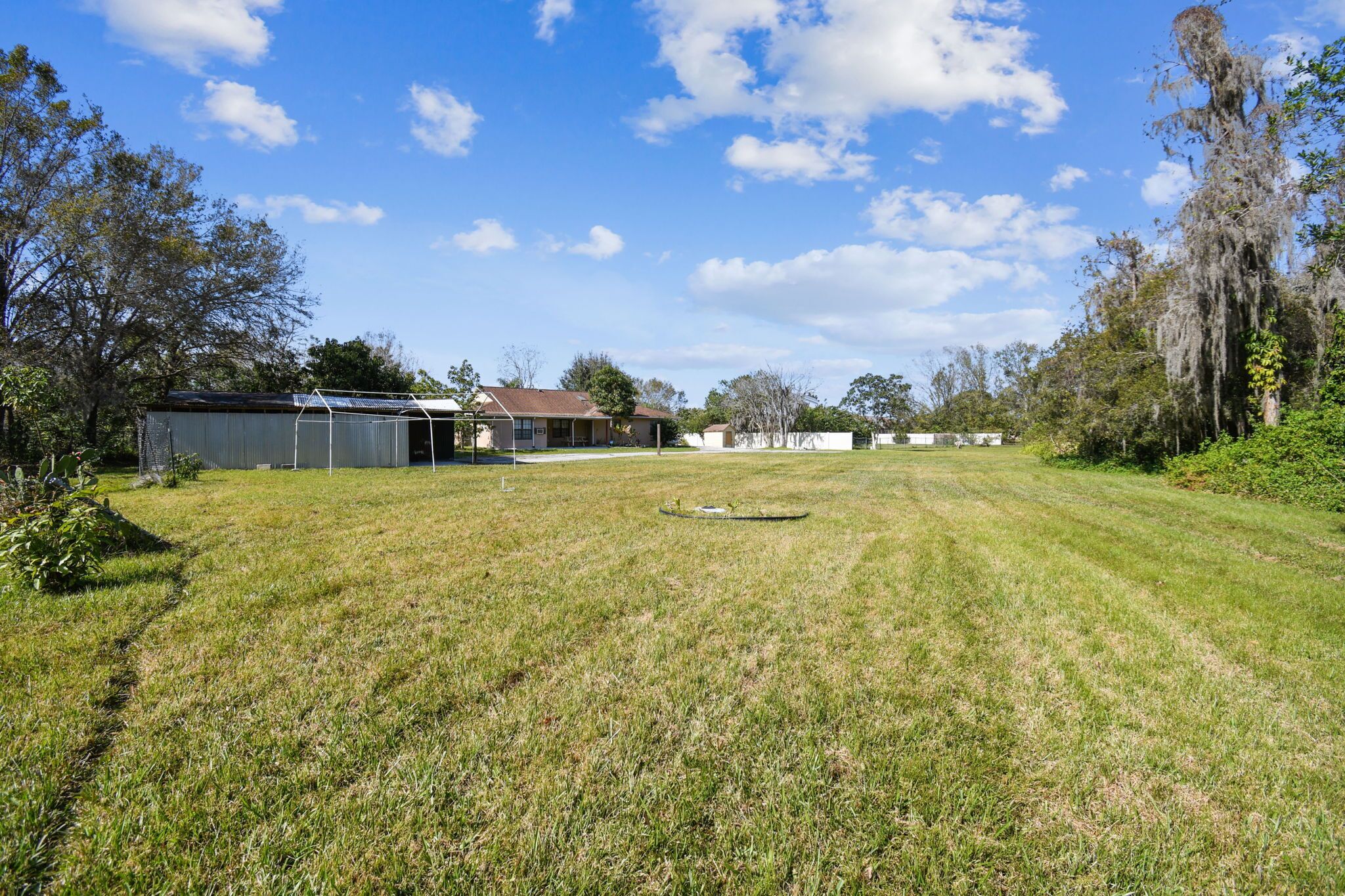 A grassy field with a building and trees.