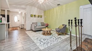 A living room with a sofa, armchair, and a round coffee table with flowers. There is a chandelier on the ceiling and a door in the background. - TRANQUILITY. Gated Estate Home. Privacy. (Kissimmee)